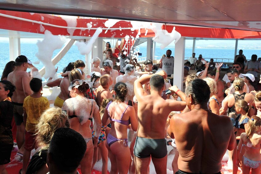 A group of people on a boat, some wearing swimsuits, with a red and white structure overhead. 3