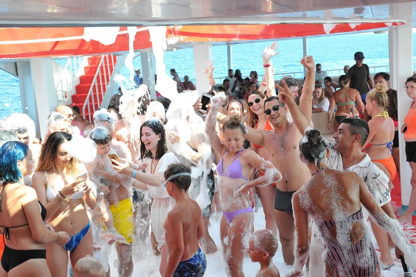 A group of people on a boat covered in foam, with a staircase and railing visible in the background. 5