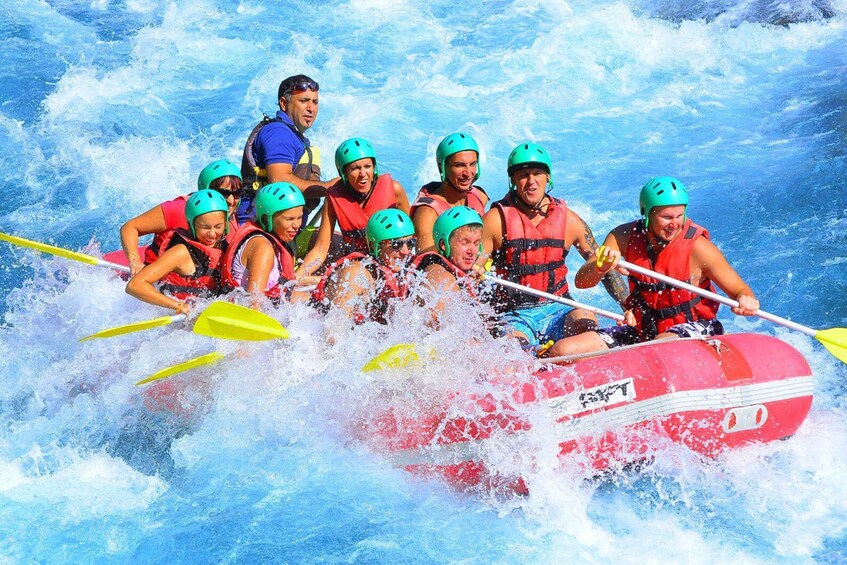 A group of people in a red inflatable raft navigating through whitewater rapids. 2
