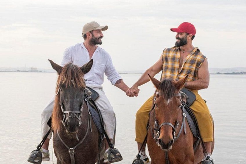 Two people on horseback by a body of water. 3