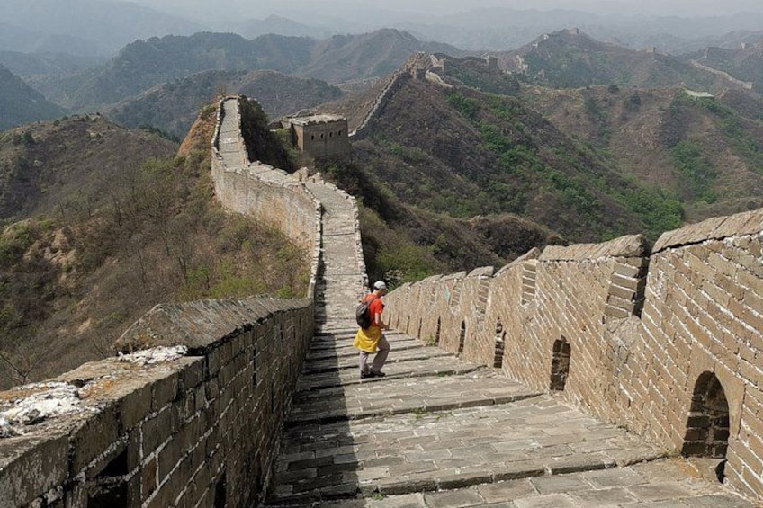 Une personne se promenant le long de la Grande Muraille de Chine, avec un paysage montagneux en arrière-plan. 2