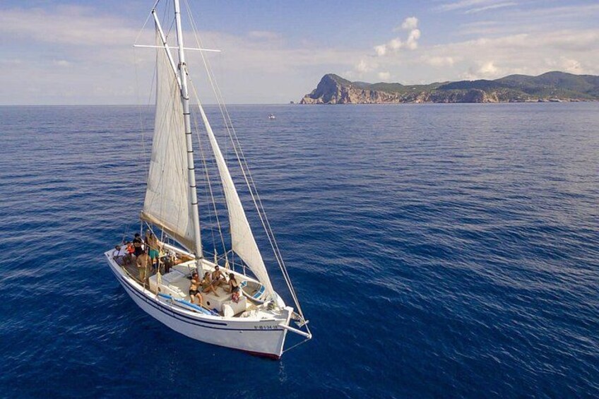 Un voilier sur l’océan, avec une côte montagneuse en arrière-plan. 2