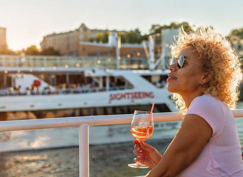 En person håller i ett vinglas och har utsikt över vattnet, och i bakgrunden syns en båt med texten ”SIGHTSEEING” (”utflykt/sightseeing”) på. 4