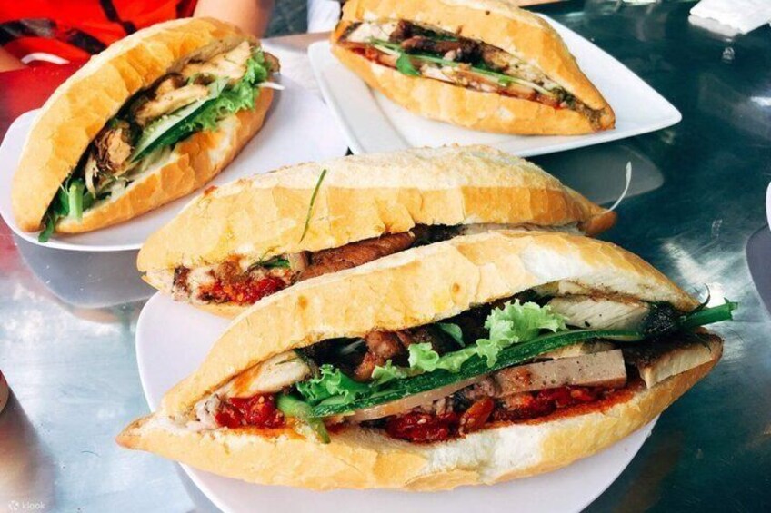 A sandwich with meat, vegetables, and sauce on a white plate. 5