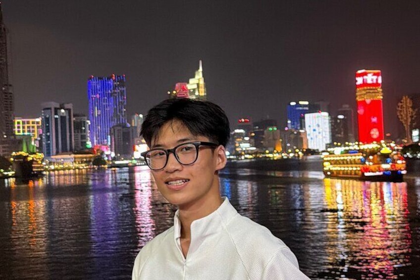 A nighttime cityscape with illuminated buildings and a river reflecting lights. 1