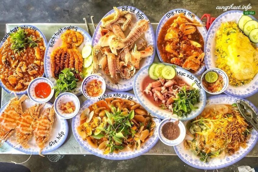 A variety of dishes on plates, including seafood and rice dishes, with labels in Vietnamese. 3