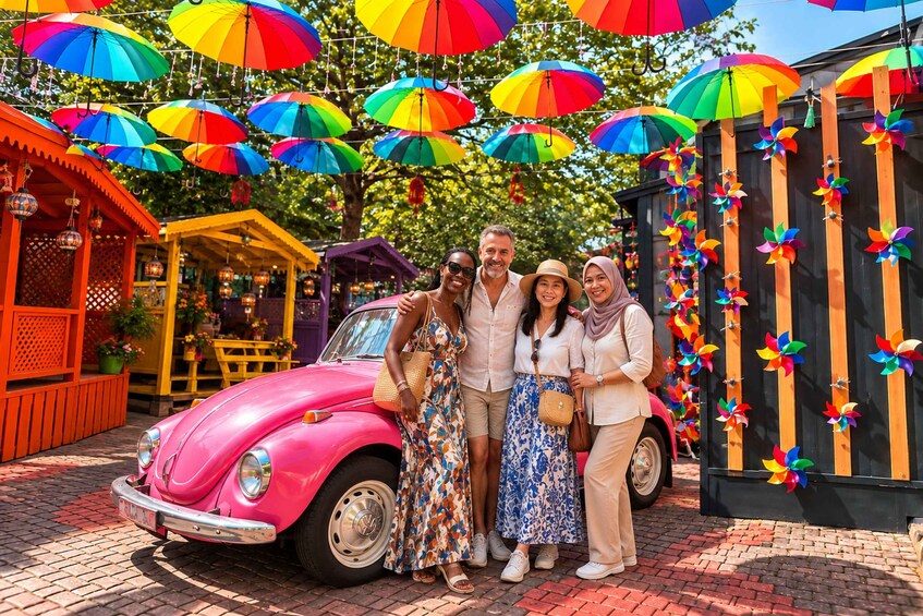 A vintage car parked in front of a colorful outdoor setting with a wooden structure and pinwheels. 2
