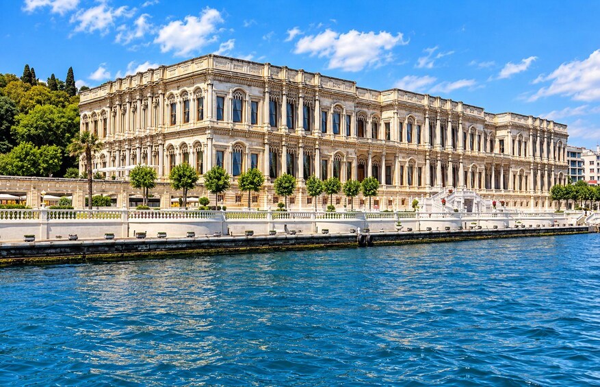 A large classical building with arched windows and columns, situated beside a calm body of water. 5