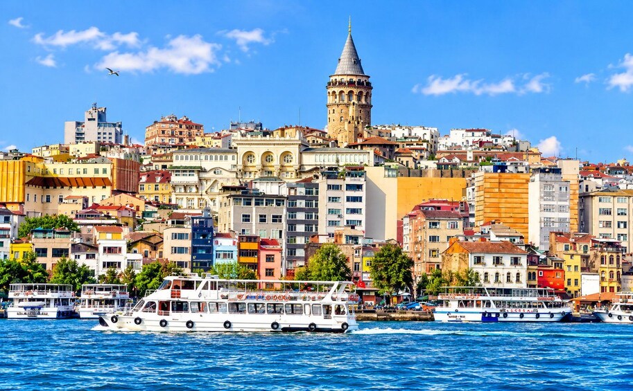 A coastal cityscape with a prominent tower, colorful buildings, and a ferry in the water. 3