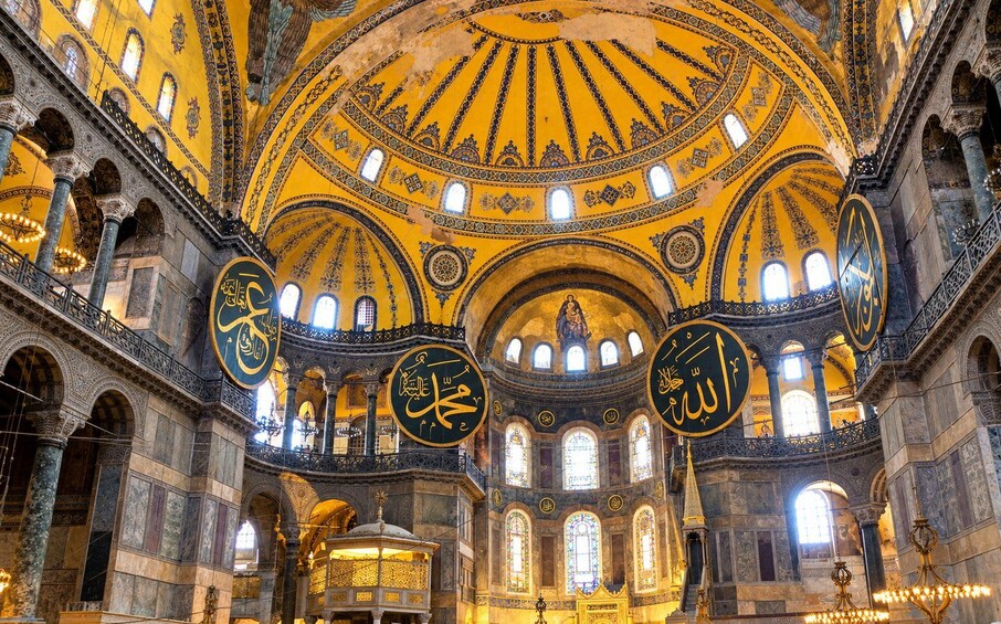 A grand interior with a domed ceiling, intricate mosaics, and Arabic calligraphy. 3