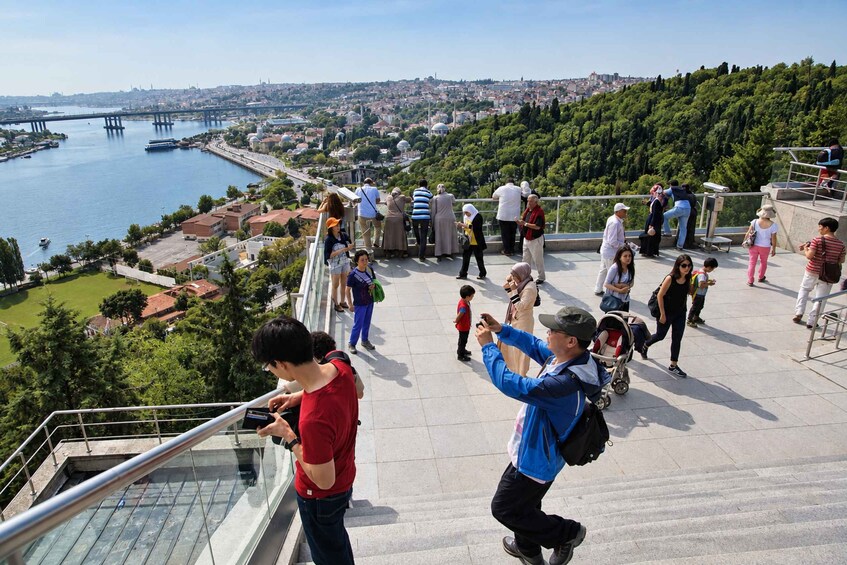 A group of people on a viewing platform overlooking a cityscape with a river and a bridge. 5