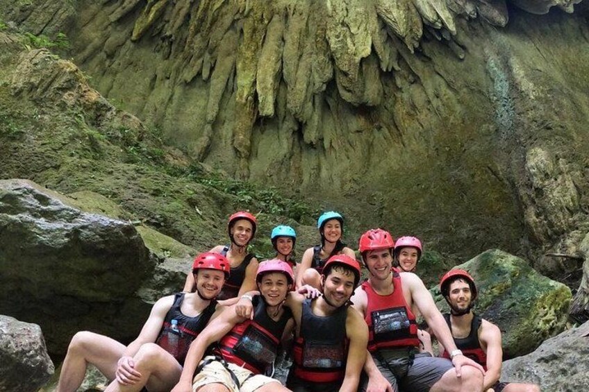 Een groep mensen met helmen en reddingsvesten zitten op rotsen in een grot. 3