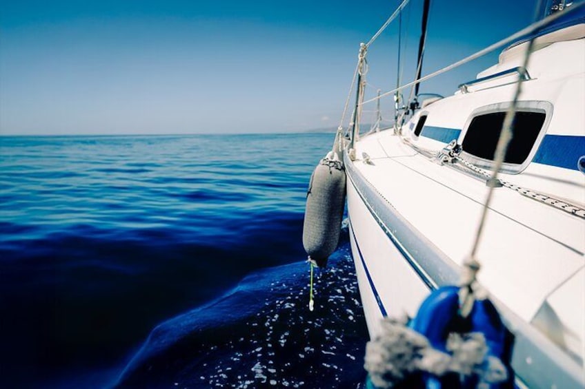 A sailboat with a blue stripe on its side, a white cabin, and a buoy attached to the side. 5