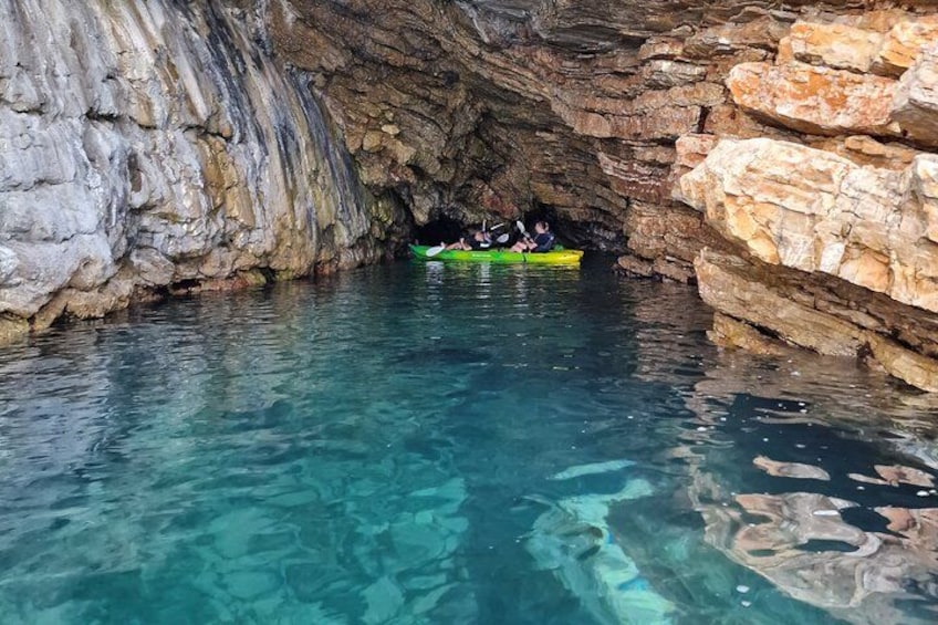 A cave with clear water and people kayaking inside. 3