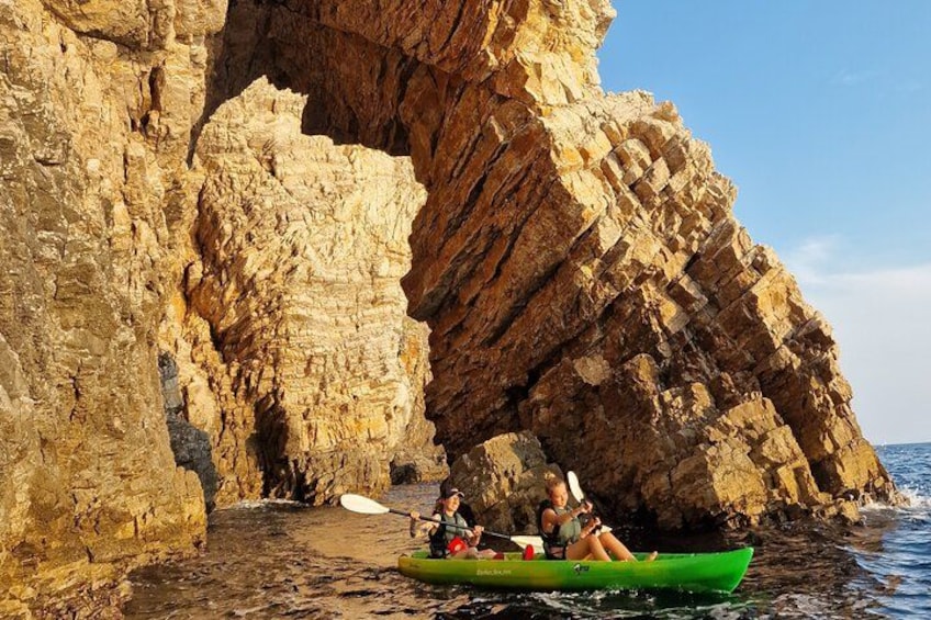 A green kayak on a rocky shoreline with a large rock formation in the background. 4