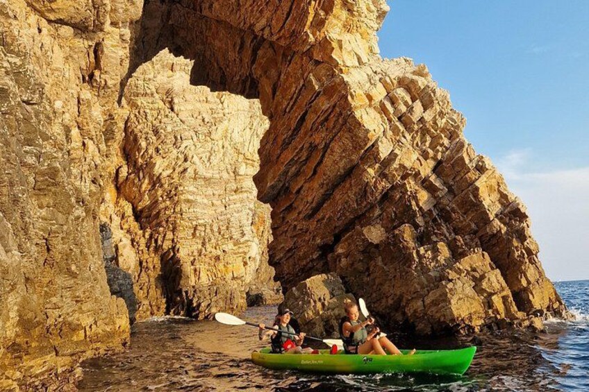 A green kayak with two people paddling near a rocky coastline. 5