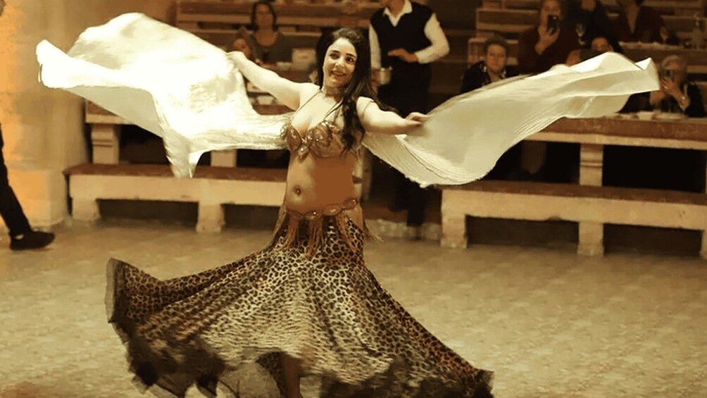 A woman in a leopard print dress dancing with her arms spread. 1