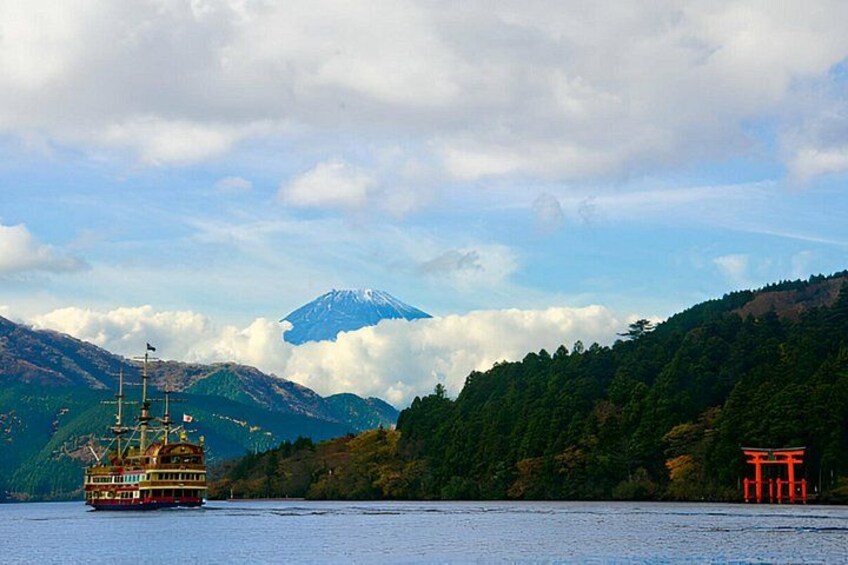 A boat on a lake, a mountain with a snow-capped peak, and a red torii gate. 2