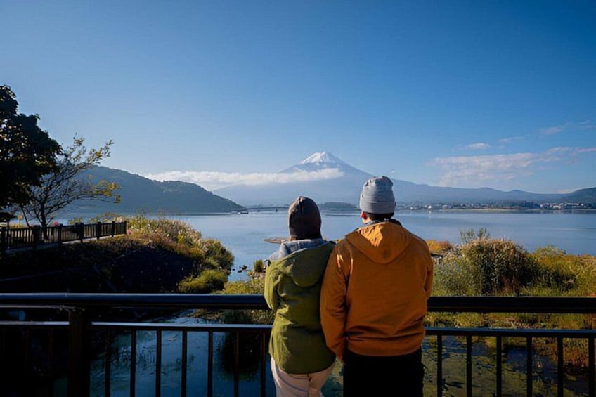 Two people standing by a railing overlooking a lake with a mountain in the background. 5