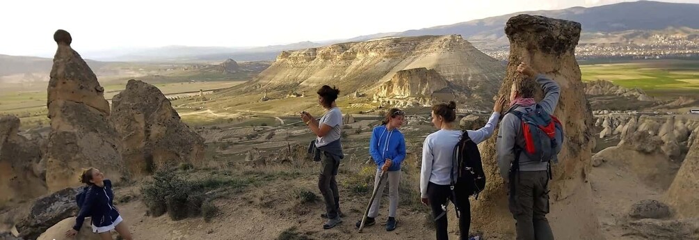 Eine Gruppe Wanderer auf einem felsigen Pfad mit Blick auf eine Wüstenlandschaft und ferne Berge. 4