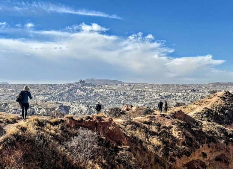Ein Wanderer auf einem Grat mit Blick auf eine weite, zerklüftete Landschaft und einen fernen Berggipfel. 1