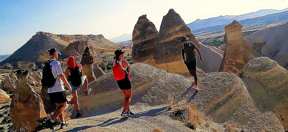 Eine Gruppe Wanderer auf einem felsigen Pfad, im Hintergrund eine gebirgige Landschaft. 2