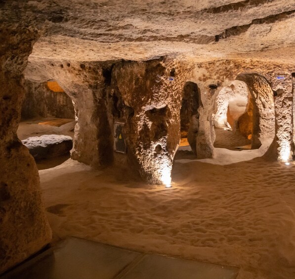 An underground cave with stalactites and stalagmites, illuminated by artificial lighting. 1