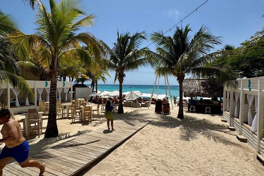 A beach with palm trees, wooden deck, and beach chairs. 5
