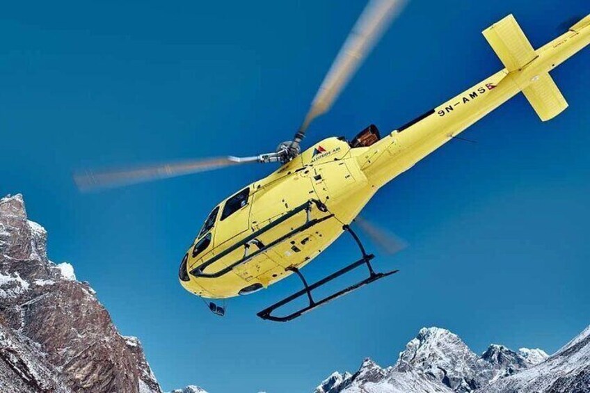 A yellow helicopter flying over snow-covered mountains. 1