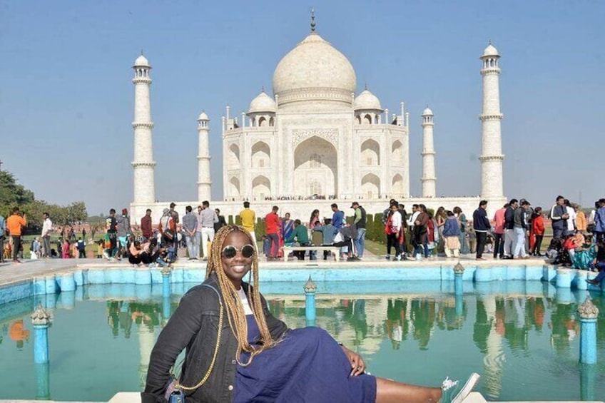 A person sitting by a pool with the Taj Mahal in the background. 5