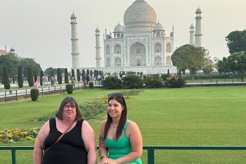 Two people sitting in front of the Taj Mahal. 1