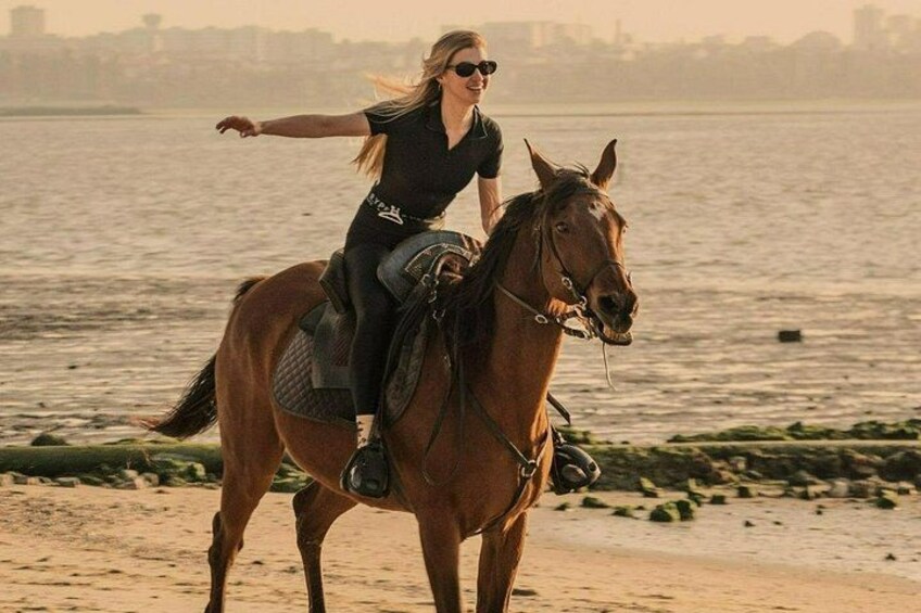 En person rider på en hest på en strand med vand i baggrunden. 4