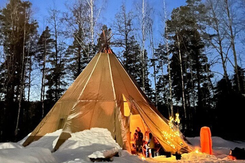 A snow-covered teepee with a fire inside, surrounded by a forest. 3