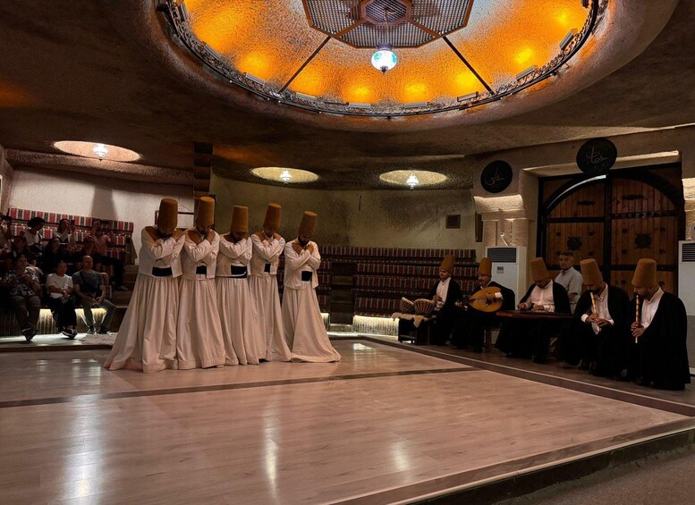 A group of women in traditional attire performing in a hall with a wooden floor and a circular ceiling design. 4