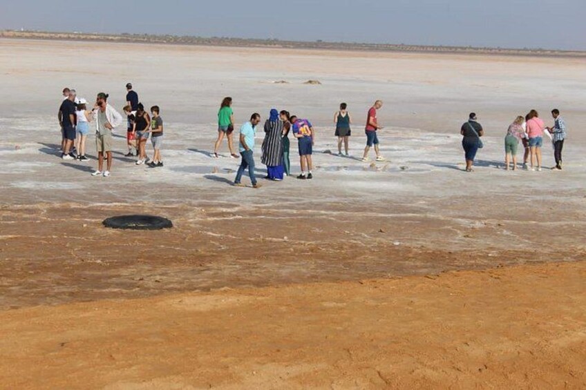 A group of people standing on a salt flat with a clear sky. 5