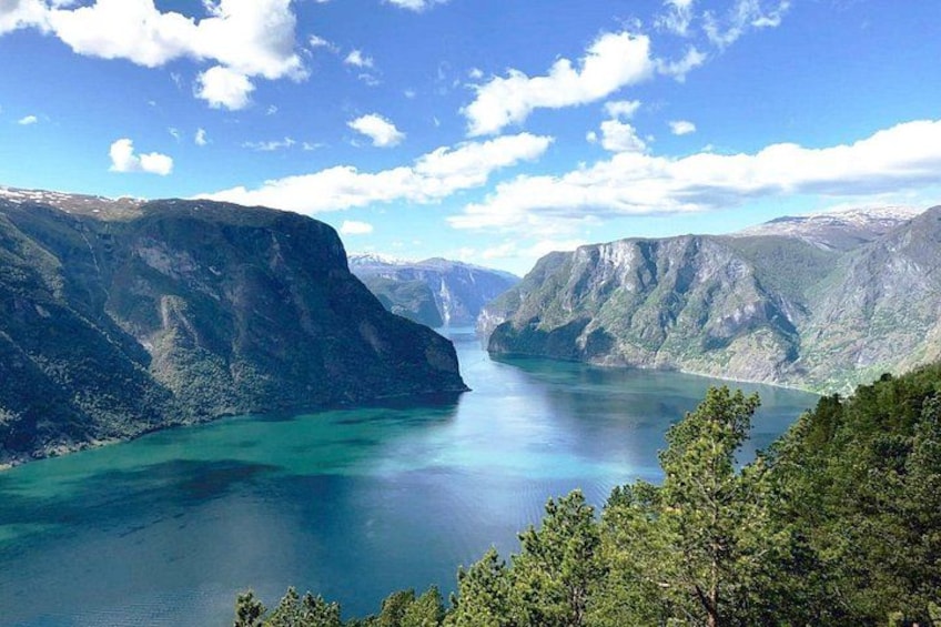 En fjord omgiven av branta klippor, lugnt turkosfärgat vatten och en klarblå himmel. 4