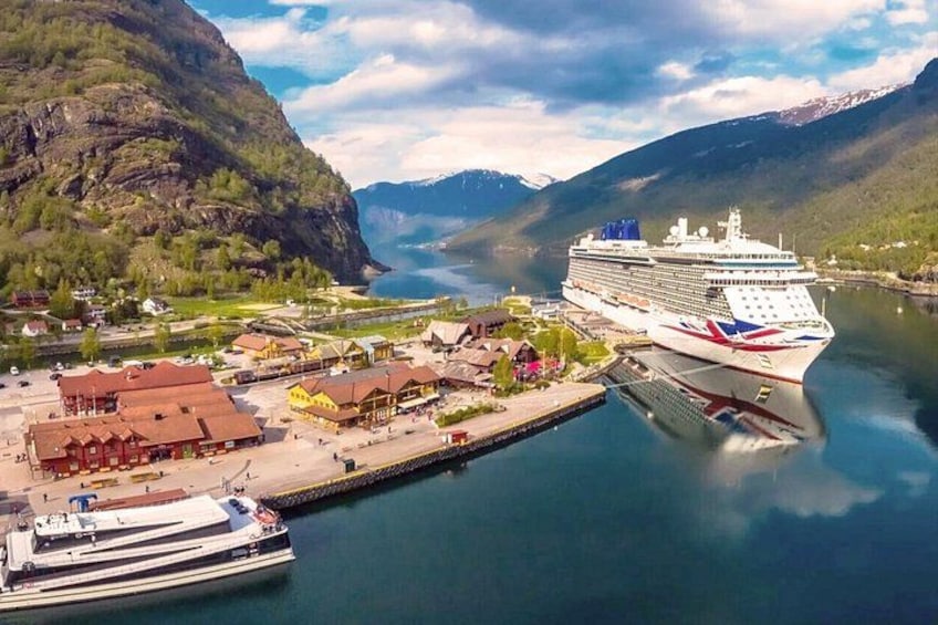 Un crucero atracado en un puerto con montañas al fondo y un pequeño pueblo. 4