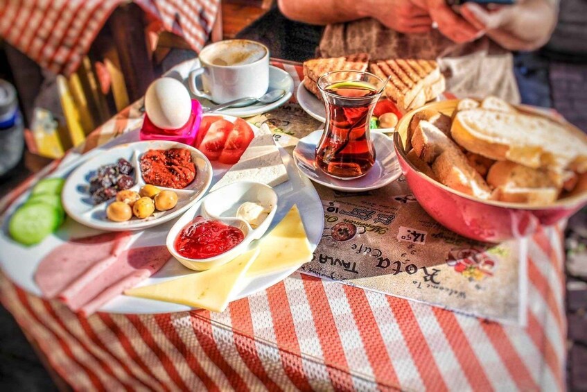 A table with various foods including bread, cheese, olives, and a cup of tea. 1