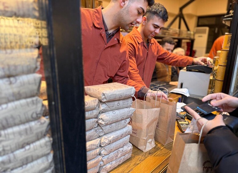 A person at a counter with a stack of packaged goods and a payment terminal. 3