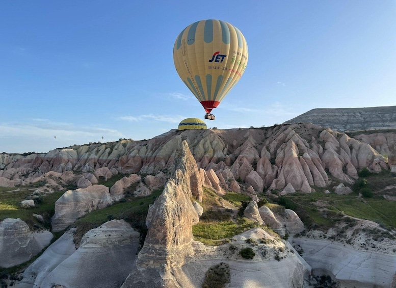 A hot air balloon with the logo 'JET' flying over a rocky landscape with unique geological formations. 5