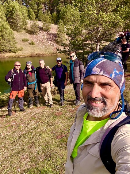 A group of people hiking near a lake surrounded by trees. 3