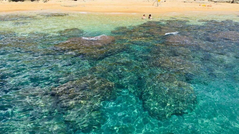 A beach with clear turquoise water and rocky formations. 4