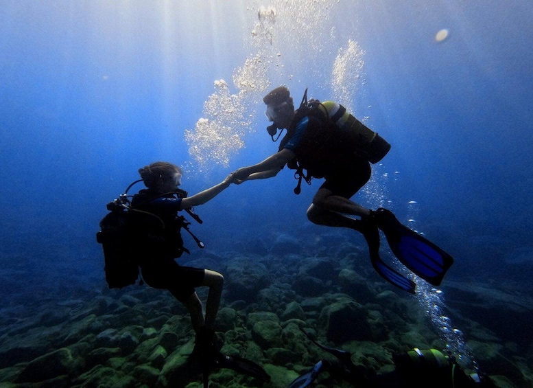 Two scuba divers underwater, one reaching out to the other. 2