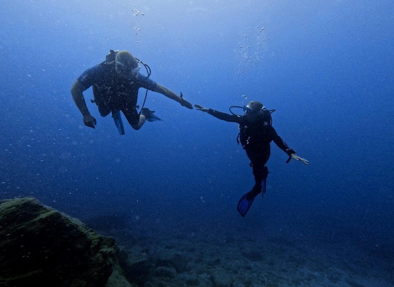 Two scuba divers underwater, one reaching out to the other. 5