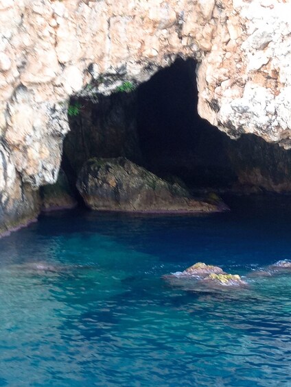A rocky cave entrance with clear blue water. 2