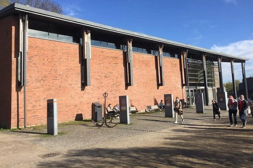 Een gebouw van baksteen met grote ramen en een overdekte gang. 4