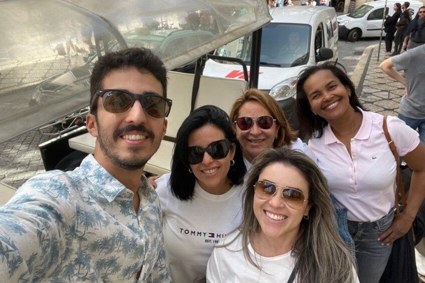 A group of people posing in front of a vehicle with a reflective surface. 2