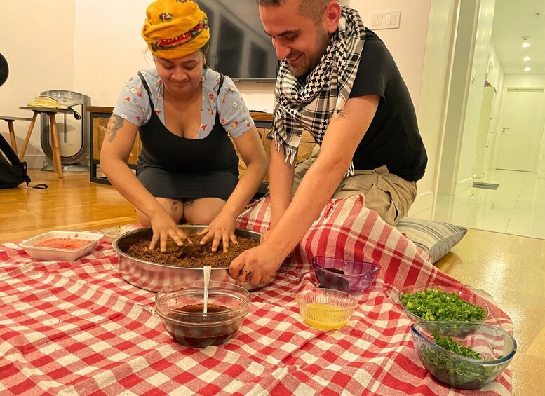 Two people preparing food on a checkered tablecloth. 1