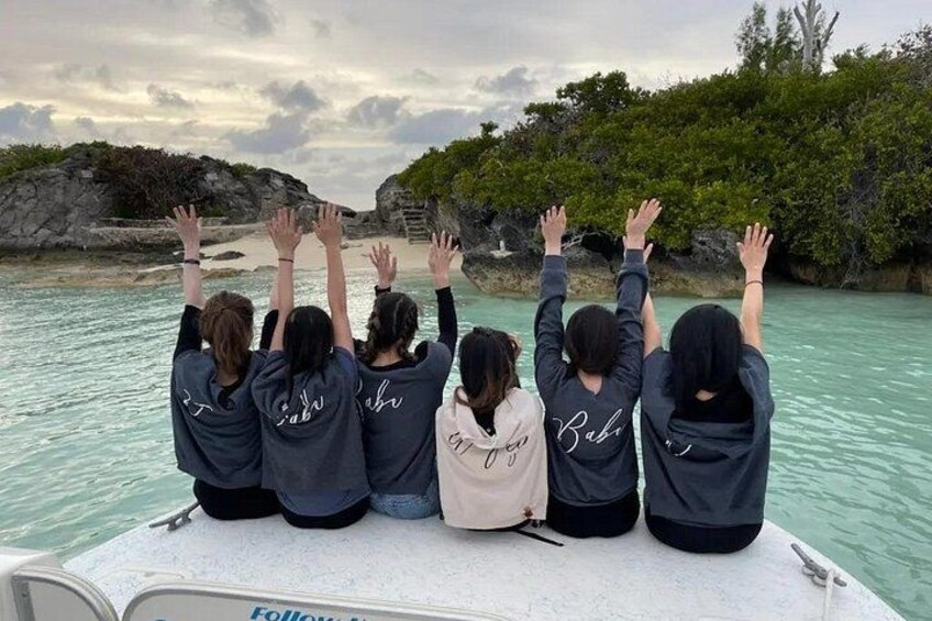 Een groep mensen op een boot, met de handen geheven, kijkt naar een rotsachtige kustlijn met water. 3