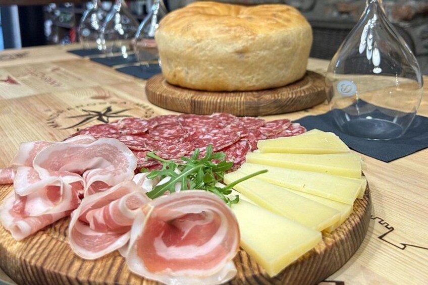 Una tabla de embutidos con diversos tipos de carne, queso y una hogaza de pan. 4
